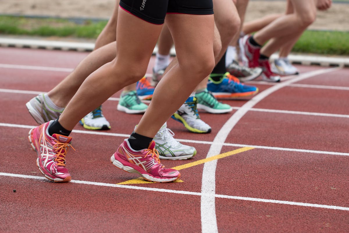 People's legs and feet on a racetrack. They're about to begin running at the same time.