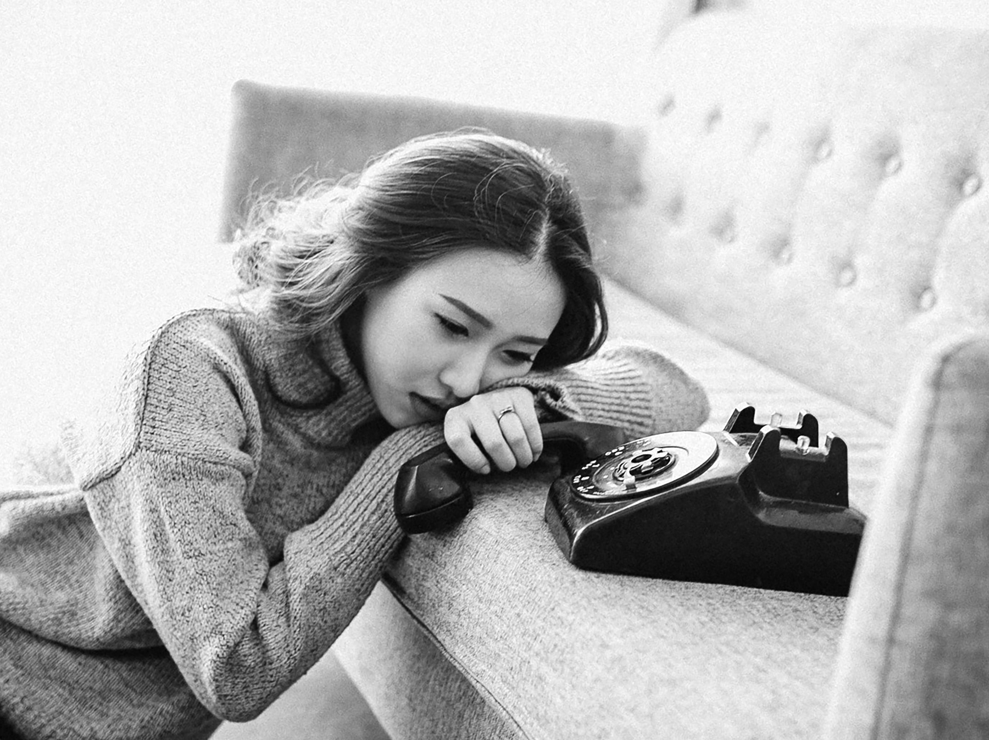 A woman morosely sitting by the phone, just waiting for it to ring